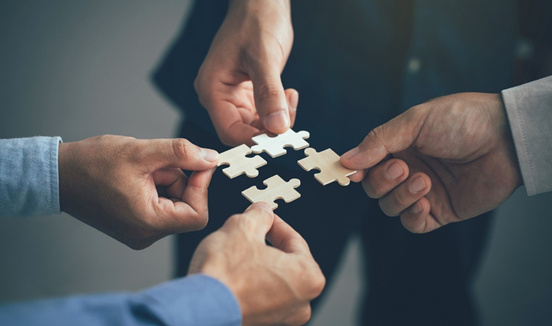 4 handen met een puzzelstukje vast